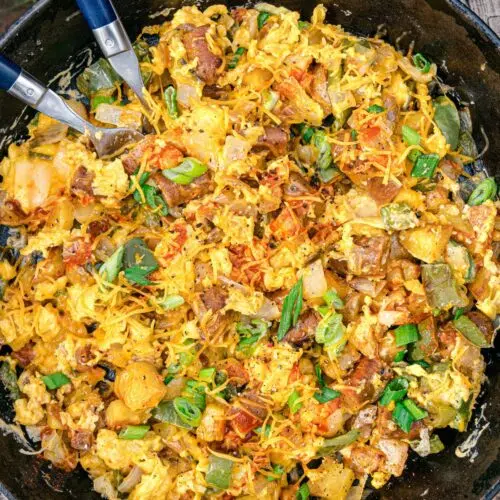 Cheesy scrambled eggs and potatoes in a cast iron skillet