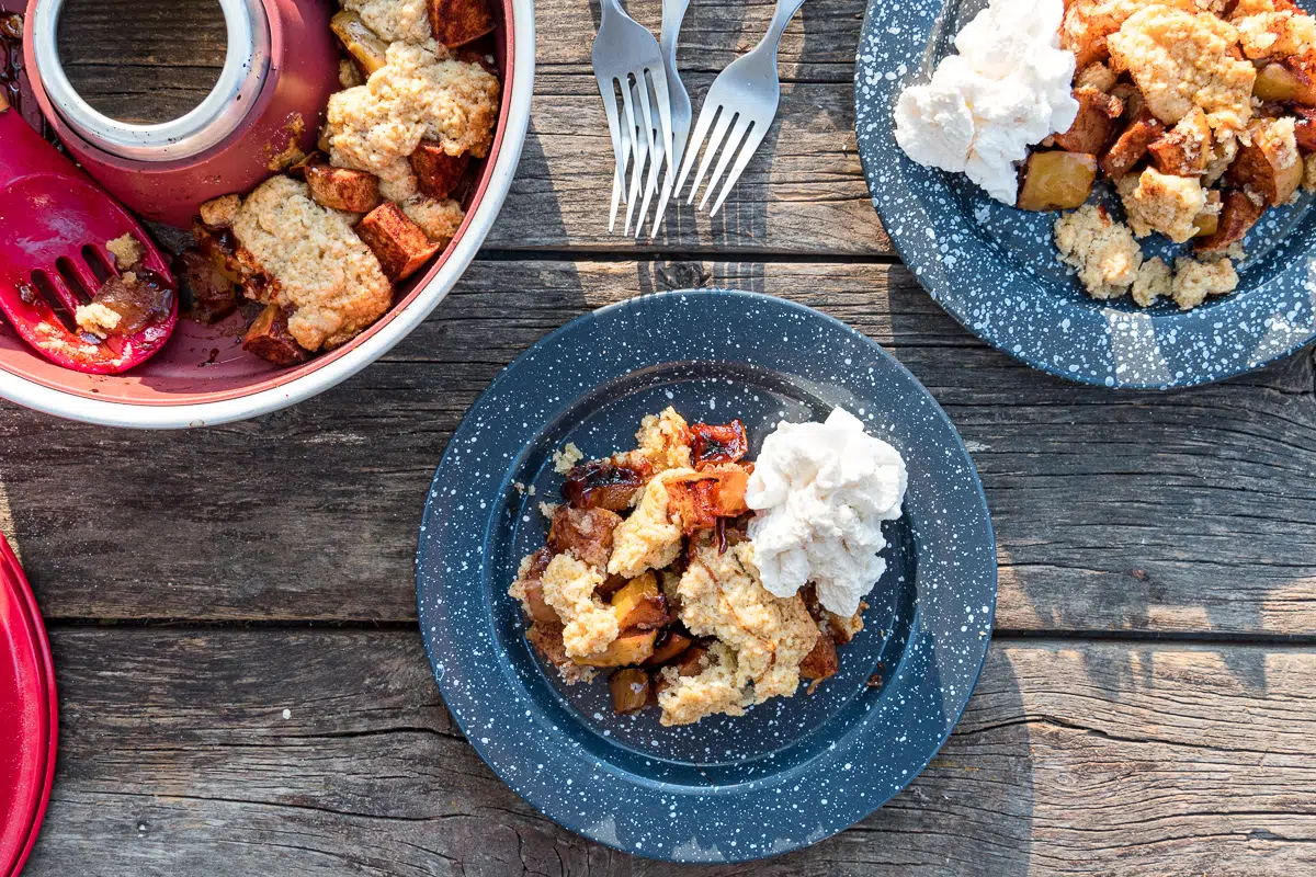 Two plates with apple cobbler and whipped cream next to an omnia oven