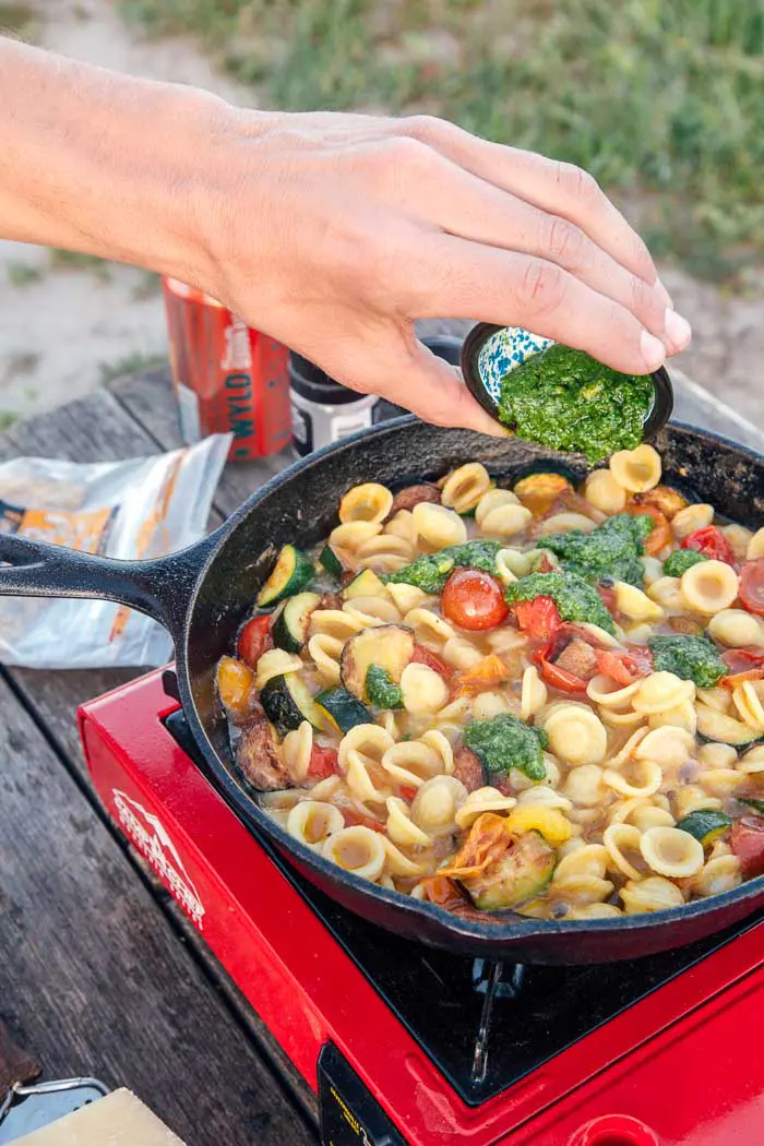 Man adding pesto into pasta.