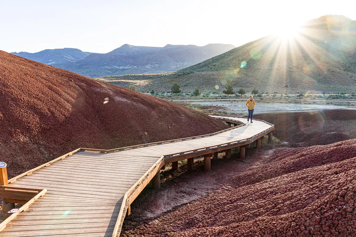 Megan walking on a wooden boardwalk through red hills