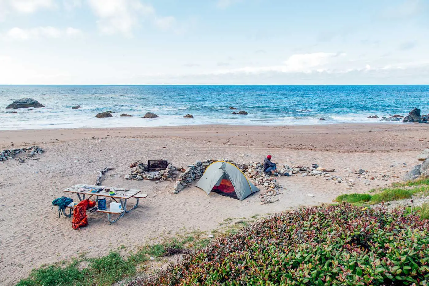 A tent set up in the sand at Parson's Landing campground with the ocean in the background.