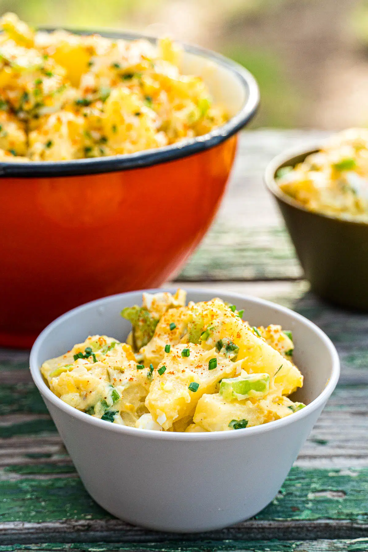 A small bowl of potato salad with a serving bowl in the background