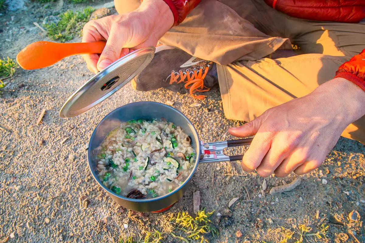 Michael sitting on the ground next to a pot on a backpacking stove