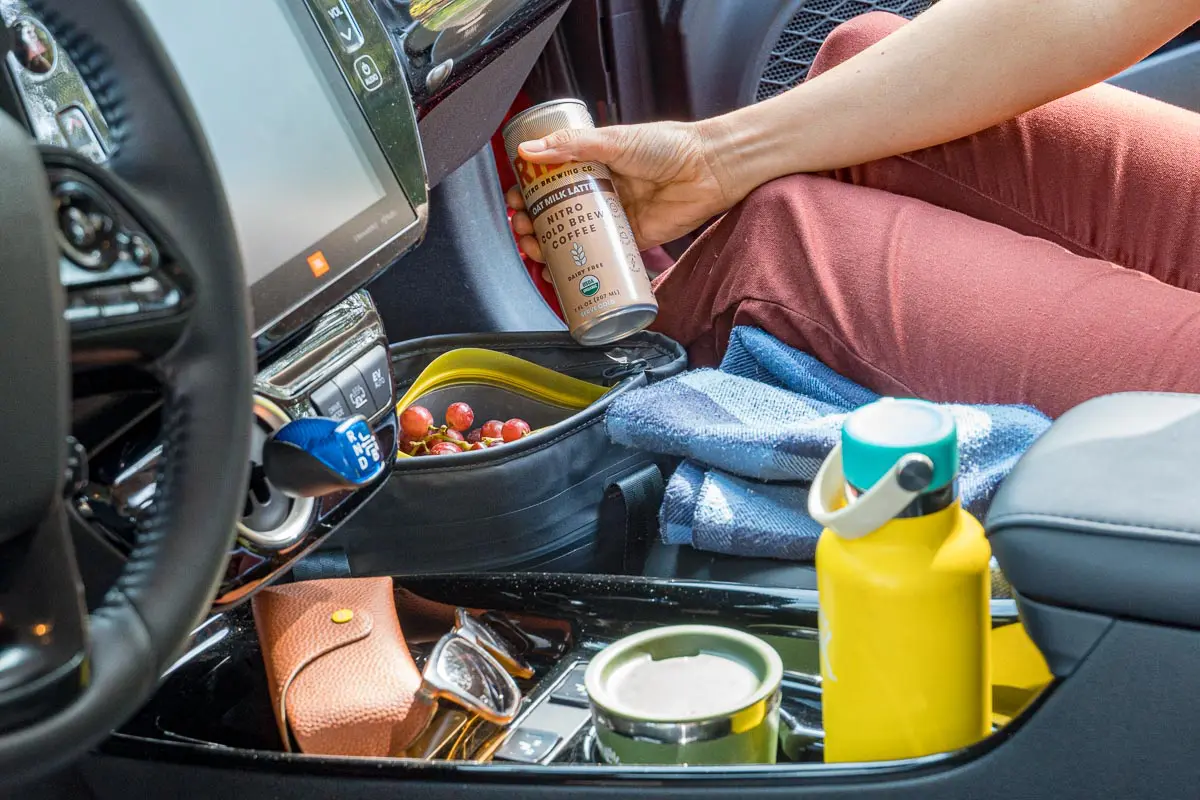 Megan in the front seat of a car holding a can of iced coffee