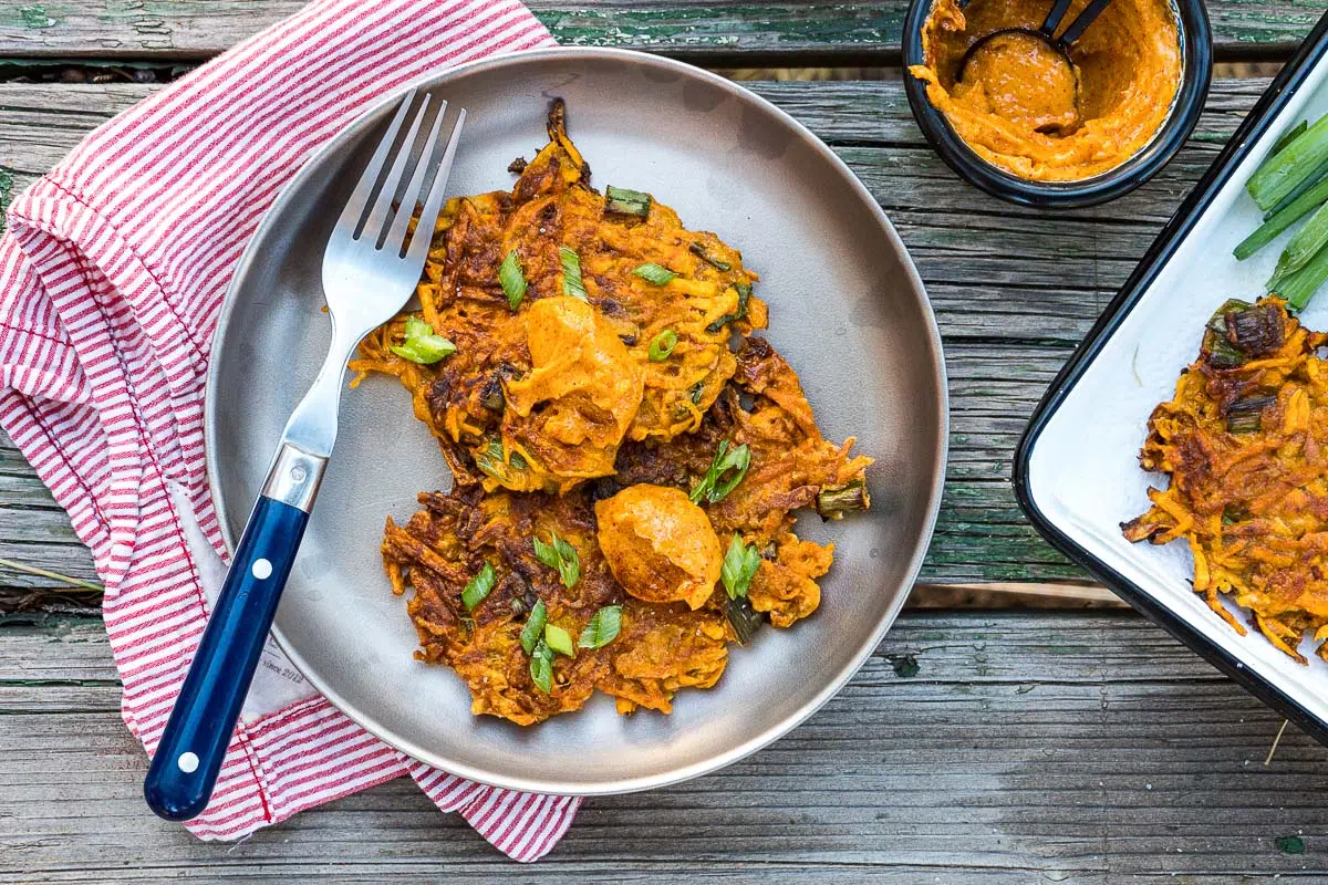 Two sweet potato fritters on a silver plate