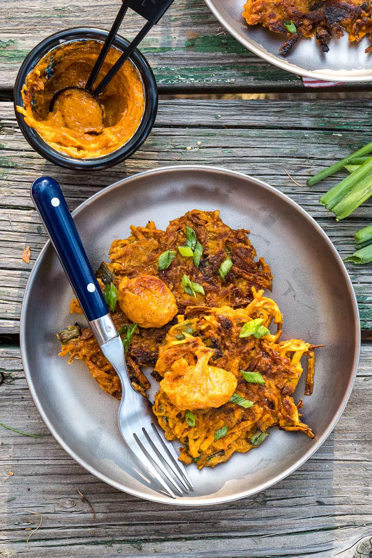 Two sweet potato fritters on a silver plate.