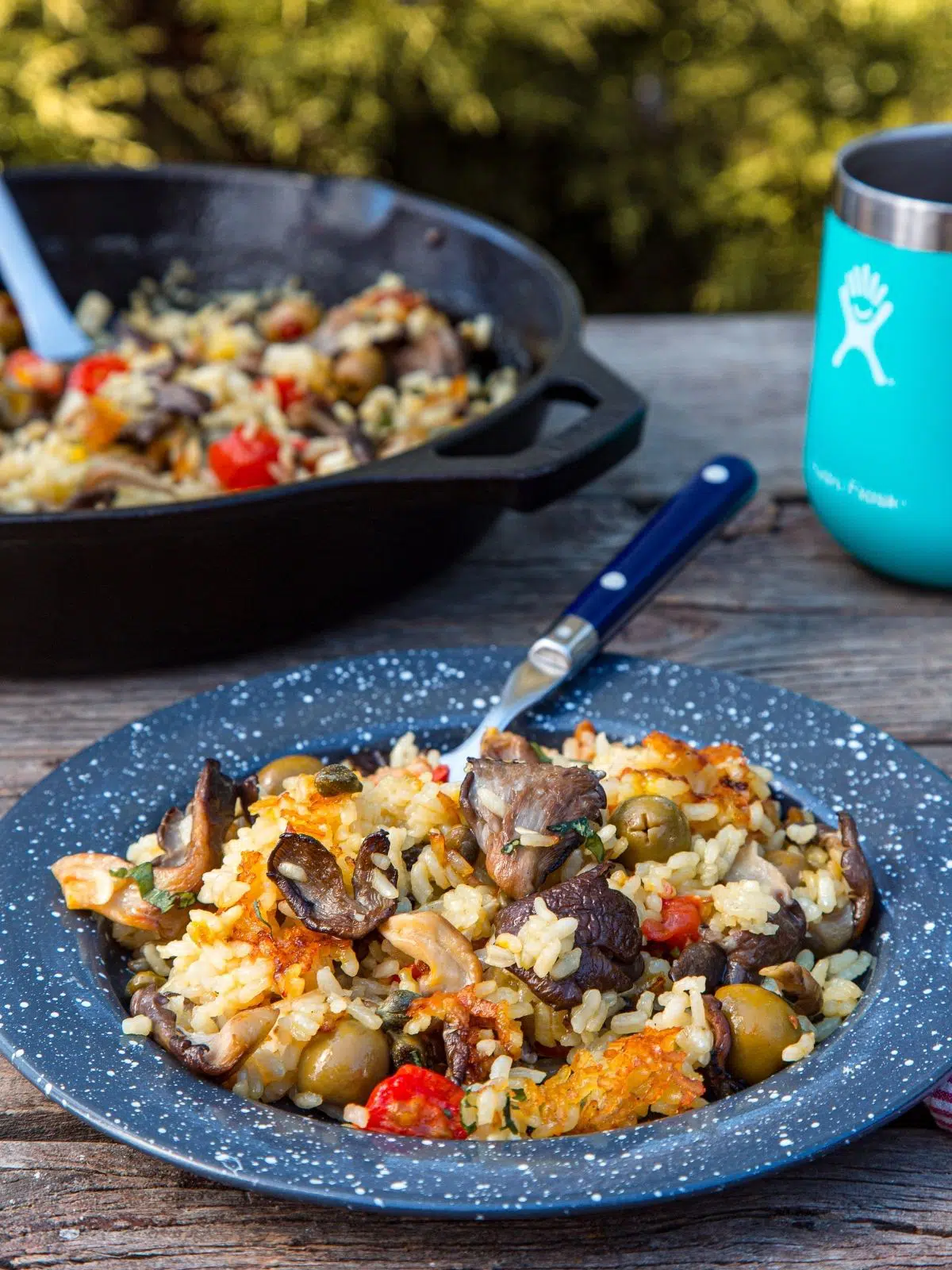 Vegan paella on a blue plate with a skillet in the background