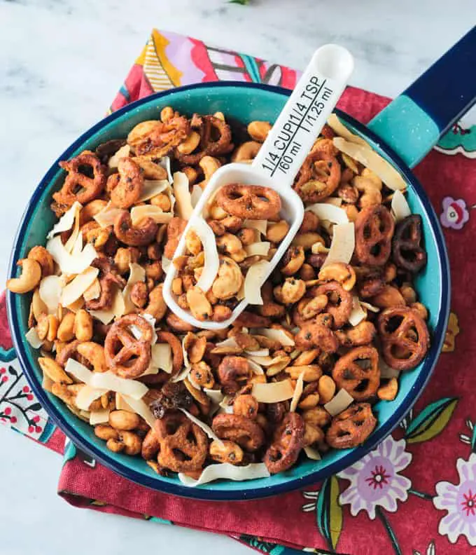 Trail mix in a blue enamel pan with a white scoop