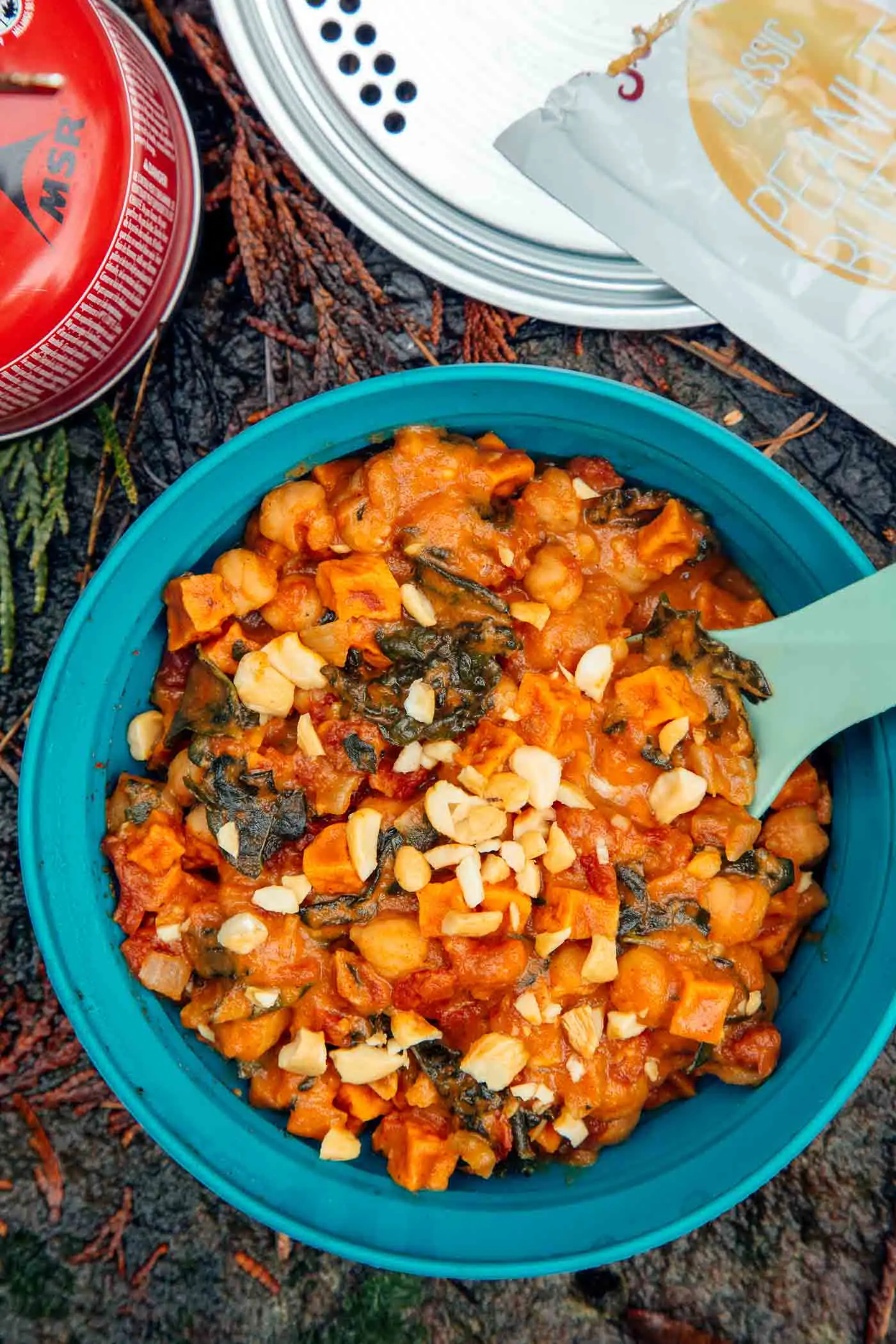 Sweet potato peanut stew in a blue bowl on a rock