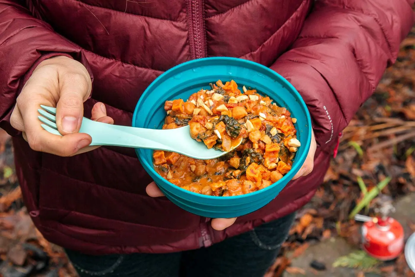 Megan holding a blue bowl of peanut stew