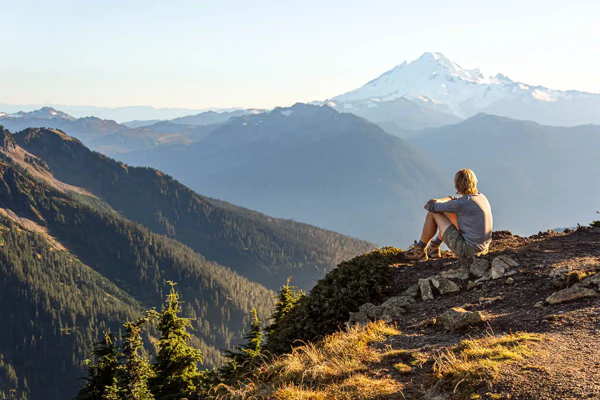 Michael sitting on rocks, looking at a mountain peak in the distance.